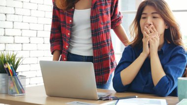 Ofis masasında kendine güvenen iki kadının birlikte çalışması mutluluktur. Bilgisayar şirketi ile çalışan takım ortakları. Asyalı iş arkadaşı arkadaşlığı gülen yüzle iş başında.