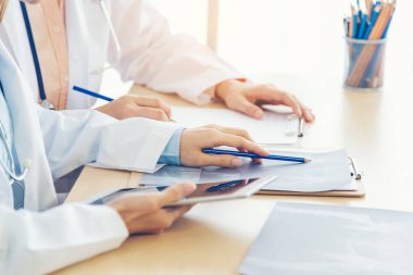 İki Asyalı kadın el doktorları buluşması reçeteli sağlık kliniği yazıyorlar. Doktor dizüstü bilgisayarı kullanarak tartışır. İki kadın doktor laboratuarının ellerini kapayarak sağlık hizmetleri ekip çalışmasını tartışıyorlar.