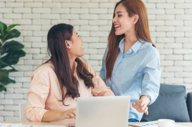 Ofis masasında kendine güvenen iki kadının birlikte çalışması mutluluktur. Bilgisayar şirketi ile çalışan takım ortakları. Asyalı iş arkadaşı arkadaşlığı gülen yüzle iş başında.