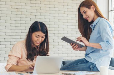 Ofis masasında kendine güvenen iki kadının birlikte çalışması mutluluktur. Bilgisayar şirketi ile çalışan takım ortakları. Asyalı iş arkadaşı arkadaşlığı gülen yüzle iş başında.