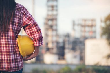 Kadın işçi elleri sarı kasklı inşaat mühendisi. Rafineri kadın petrol endüstrisi sarı işçi miğferini tutuyor. Rafineri endüstrisi mühendisi üretimi