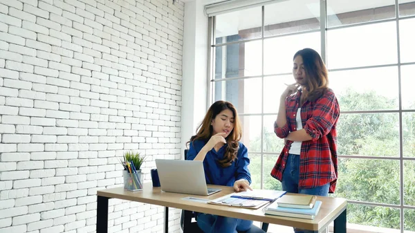 Asyalı iş arkadaşı arkadaşlığı, gülen yüzle. Mutluluk iki kadın meslektaşın ofis masasında takım çalışması. Bilgisayar şirketi ile çalışan takım ortakları
