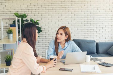 Ofis masasında kendine güvenen iki kadının birlikte çalışması mutluluktur. Bilgisayar şirketi ile çalışan takım ortakları. Asyalı iş arkadaşı arkadaşlığı gülen yüzle iş başında.