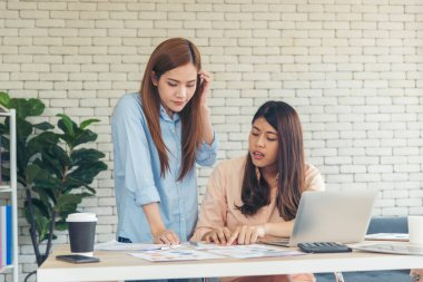 Ofis masasında kendine güvenen iki kadının birlikte çalışması mutluluktur. Bilgisayar şirketi ile çalışan takım ortakları. Asyalı iş arkadaşı arkadaşlığı gülen yüzle iş başında.