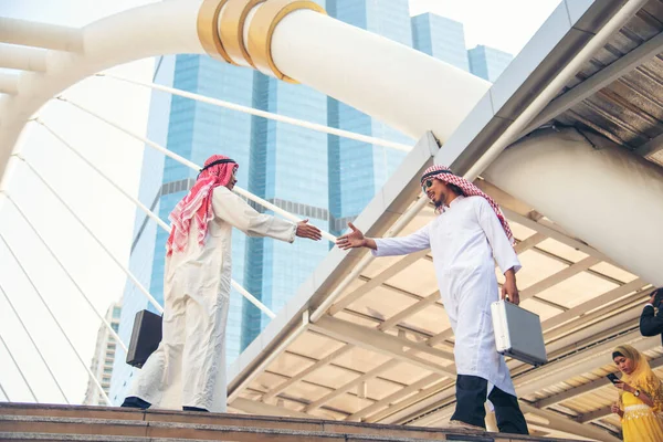 Arab Businessman Muslim dress shaking hands together in modern city UAE background. Muslim Men Teamwork business partner handshake with Partnership. diversity multiracial arab people trust commitment