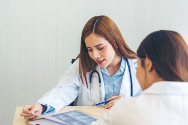 İki Asyalı kadın doktor dizüstü bilgisayarlı hasta danışmanlığı kullanarak doktorun muayenehanesiyle görüşmeyi tartışıyor. Asya tıp laboratuarındaki genç kadınlar birlikte sağlık hizmetleri ekip çalışmasını tartışıyorlar.