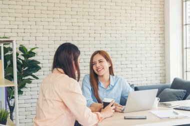 Ofis masasında kendine güvenen iki kadının birlikte çalışması mutluluktur. Bilgisayar şirketi ile çalışan takım ortakları. Asyalı iş arkadaşı arkadaşlığı gülen yüzle iş başında.
