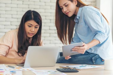 Ofis masasında kendine güvenen iki kadının birlikte çalışması mutluluktur. Bilgisayar şirketi ile çalışan takım ortakları. Asyalı iş arkadaşı arkadaşlığı gülen yüzle iş başında.