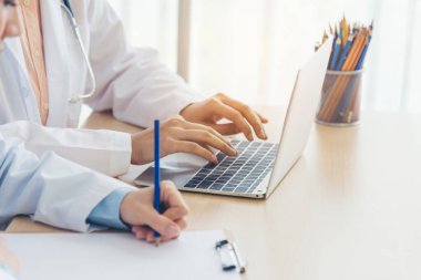 İki Asyalı kadın doktor dizüstü bilgisayarlı hasta danışmanlığı kullanarak doktorun muayenehanesiyle görüşmeyi tartışıyor. Asya tıp laboratuarındaki genç kadınlar birlikte sağlık hizmetleri ekip çalışmasını tartışıyorlar.