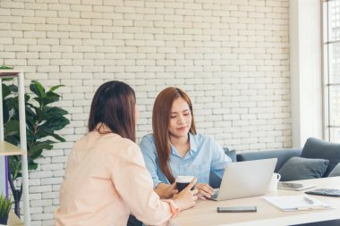 Finansal grafik grafiklerini okuyan iki Asyalı kadın pazarlama verilerini analiz etmeyi planlıyor. Asyalı takım çalışanı ofis firması. Şirket masasında dizüstü bilgisayarla iki iş kadını buluşması..