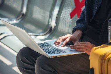 Asyalı genç adam, dizüstü bilgisayar kullanan yeni normal yolcu. Yüz maskesi takıyor. Uçak salonunda sosyal mesafeli oturuyor. Yeni normal erkek yolcu salgını uçakla geliyor. Yeni normal turist gezisi