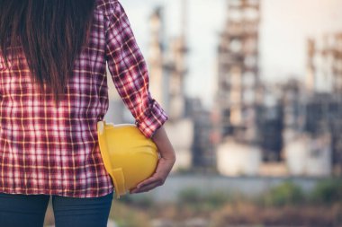 Kadın işçi elleri sarı kasklı inşaat mühendisi. Rafineri kadın petrol endüstrisi sarı işçi miğferini tutuyor. Rafineri endüstrisi mühendisi üretimi