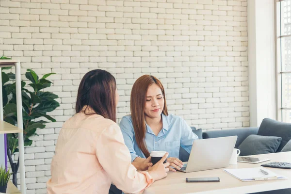 Two asian Female freelance reading financial graph charts Planning analyzing marketing data. Asian people team working office firm. Two businesswomen team meeting using laptop at company office desk.