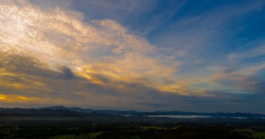 Mavi altın gökyüzü gün doğumu dramatik manzara dağları. Şafak vakti altın rengi alacakaranlık zamanı güneş ışığıyla bulutlu manzara. Dağ manzarasında dramatik bir gün batımı. Güzel manzara sisli tepeler alacakaranlık vakti
