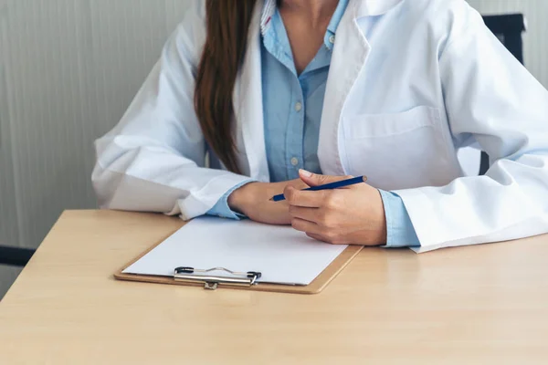 Close up hands of women doctor write prescription medical lab hospital. Crop asian women hand doctors working in medical clinic looking CAT scan xray film. Doctor with stethoscope writing on notepad