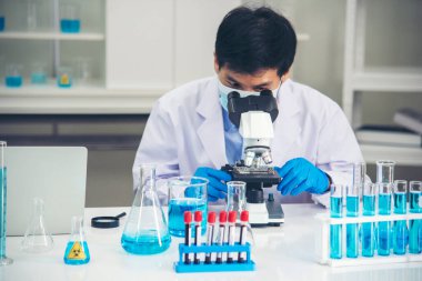 Bilim adamı bilim laboratuarındaki mikroskop araştırmalarını inceliyor. Asyalı bilim adamı laboratuvar kimya laboratuvarlarını arıyor. Covid-19 Coronavirus biyokimya araştırma deneyi aşı konsepti