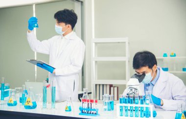 İki Asyalı bilim adamı kimya bilimi tüpü deney tüpü antikor örneğini kovid-19 virüsüne karşı laboratuvar geliştirmek için depoluyorlar. Kimya Laboratuarı 'nda bilim adamı danışmanı, analizi