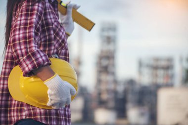 Rafineri kadın petrol endüstrisi sarı işçi miğferini tutuyor. Kadın işçi elleri sarı kasklı inşaat mühendisi. Rafineri endüstrisi mühendisi üretimi