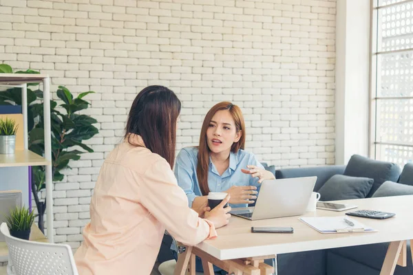 Ofis masasında kendine güvenen iki kadının birlikte çalışması mutluluktur. Bilgisayar şirketi ile çalışan takım ortakları. Asyalı iş arkadaşı arkadaşlığı gülen yüzle iş başında.