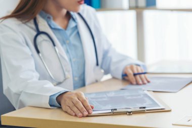 Kadın doktorların eli kapalı reçeteli tıp laboratuarı hastanesi yazıyorlar. Ekinci Asyalı kadınlar klinikte çalışan doktorlara röntgen filmi çektiriyorlar. Not defterine steteskop yazan bir doktor.