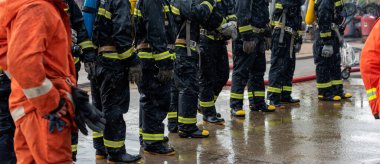 Firefighter Rescue team training in fire fighting extinguisher. Firefighter teamwork fighting with flame using fire hose chemical water foam spray engine. Fireman wear hard hat, safety suit uniform