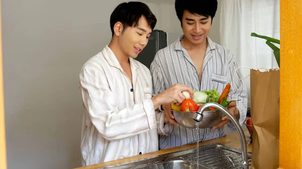 Asian two Man hands wash cleaning fresh vegetable in kitchen. Happy Asian gay couple homosexual cooking together in kitchen wash vegetable organic salad healthy home cook. LGBTQIA lifestyle concept
