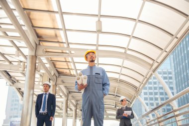 İnşaat mühendisi takımları modern kentteki inşaat sahasında birlikte çalışan işçi kaskı takıyorlar. Foreman Endüstri Mühendislik Mühendisliği ekip çalışması. Asya endüstrisi profesyonel takımı