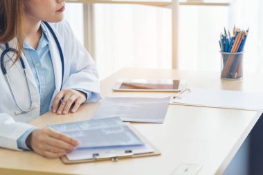 Kadın doktorların eli kapalı reçeteli tıp laboratuarı hastanesi yazıyorlar. Ekinci Asyalı kadınlar klinikte çalışan doktorlara röntgen filmi çektiriyorlar. Not defterine steteskop yazan bir doktor.