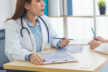 Kadın doktorların eli kapalı reçeteli tıp laboratuarı hastanesi yazıyorlar. Ekinci Asyalı kadınlar klinikte çalışan doktorlara röntgen filmi çektiriyorlar. Not defterine steteskop yazan bir doktor.