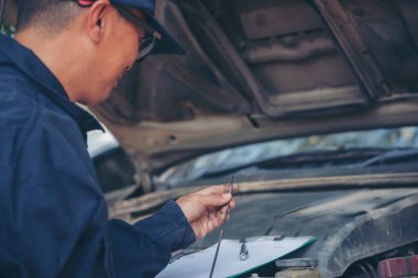 Araba tamircisi, servis alanında motor yağı mekaniğini elle kontrol ediyor. El kapatma adam motor yağı seviyesini kontrol et. Dipstick 'i bul, temizle, motor yağı doldurmadan önce dipstick seviyesini kontrol et.