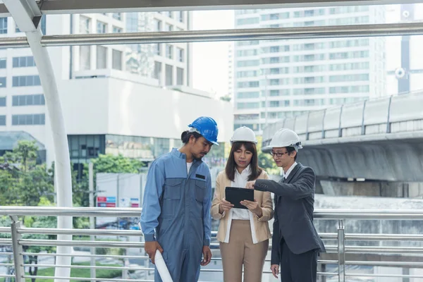 Civil engineer teams meeting working together wear worker helmets hardhat on construction site in modern city. Foreman industry project manager engineer teamwork. Asian industry professional team