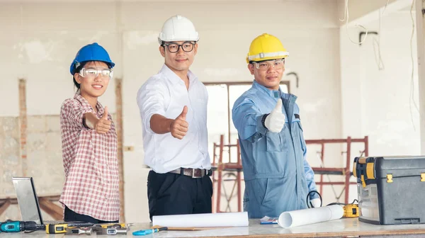 Construction engineer teamwork Safety Suit Trust Team Holding White Yellow Safety hard hat Security Equipment on Construction Site. Hardhat Protect Head for Civil Construction Engineer Concept