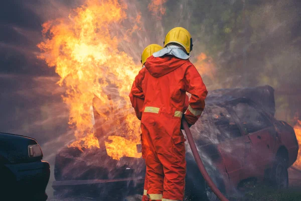 Firefighter fighting with flame using fire hose chemical water foam spray engine. Fireman wear hard hat, body safe suit uniform for protection. Rescue training in fire fighting extinguisher