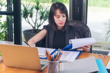 Akıllı telefon kullanan bir iş kadını, ofis masasında dizüstü bilgisayar. Finansal grafik grafikleri okuyan serbest çalışan bir kadın pazarlama verilerini analiz etmeyi planlıyor. Şirkette çalışan genç bir kadının elleri..