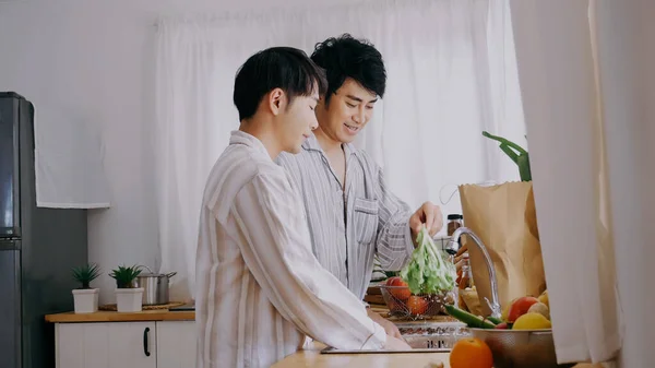 Asian people happy time smile, laugh in kitchen. Best friend LGBTQ lifestyle. Happy Asian gay couple homosexual cooking together in kitchen prepare fresh vegetable make organic salad healthy food.