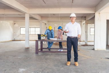 İnşaat mühendisi takım çalışması güvenlik ekibi, inşaat sahasında beyaz sarı şapkalı güvenlik ekipmanı tutuyor. Hardhat İnşaat Mühendisliği Mühendisliği Yöneticisini Koru