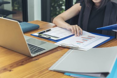 Akıllı telefon kullanan bir iş kadını, ofis masasında dizüstü bilgisayar. Finansal grafik grafikleri okuyan serbest çalışan bir kadın pazarlama verilerini analiz etmeyi planlıyor. Şirkette çalışan genç bir kadının elleri..