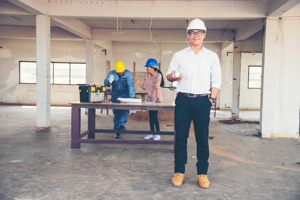 Construction engineer teamwork Safety Suit Trust Team Holding White Yellow Safety hard hat Security Equipment on Construction Site. Hardhat Protect Head for Civil Construction Engineer Concept