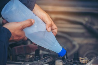 Araba tamircisi elleri araba aküsü mekanik servisi için arıtılmış arıtılmış su döküyor. Kapatın elleri adamım. Deiyonize edilmiş sıvı su şişesini garajdaki mobil araba servisinde tutun.