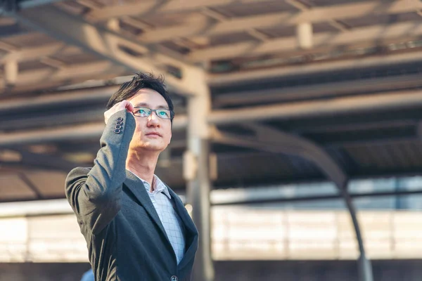 Asian businessman wear suit, eye glasses standing street in modern city. Portrait Young handsome asian man look at bright future smart, confident. Entrepreneur executive man cityscape outside office