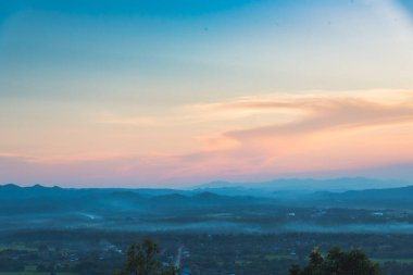 Mavi altın gökyüzü gün doğumu dramatik manzara dağları. Şafak vakti altın rengi alacakaranlık zamanı güneş ışığıyla bulutlu manzara. Dağ manzarasında dramatik bir gün batımı. Güzel manzara sisli tepeler alacakaranlık vakti