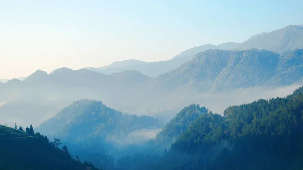 Dramatic sunset over mountain landscape. Beautiful landscape foggy hills twilight time. Blue golden sky sunrise dramatic beautiful landscape mountain. Dawn sky gold dusk time cloudscape with sunlight