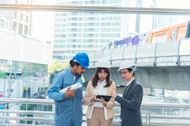 İnşaat mühendisi takımları modern kentteki inşaat sahasında birlikte çalışan işçi kaskı takıyorlar. Foreman Endüstri Mühendislik Mühendisliği ekip çalışması. Asya endüstrisi profesyonel takımı