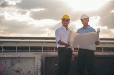 İnşaat mühendisi takımları modern kentteki inşaat sahasında birlikte çalışan işçi kaskı takıyorlar. Foreman Endüstri Mühendislik Mühendisliği ekip çalışması. Asya endüstrisi profesyonel takımı