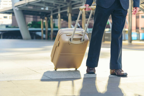 Businessman walking with luggage in business trip. Focus on man legs boarding travel arrival terminal. Business travel trip holding suitcase at airport. Young business man traveller concept