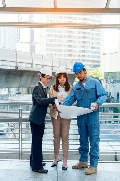 Civil engineer teams meeting working together wear worker helmets hardhat on construction site in modern city. Foreman industry project manager engineer teamwork. Asian industry professional team