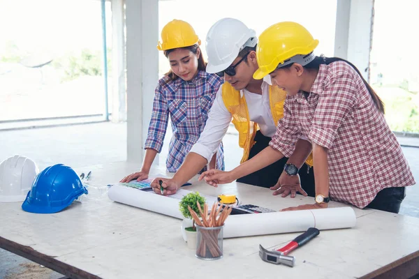 Civil engineer teams meeting working together wear worker helmets hardhat on construction site in modern city. Foreman industry project manager engineer teamwork. Asian industry professional team