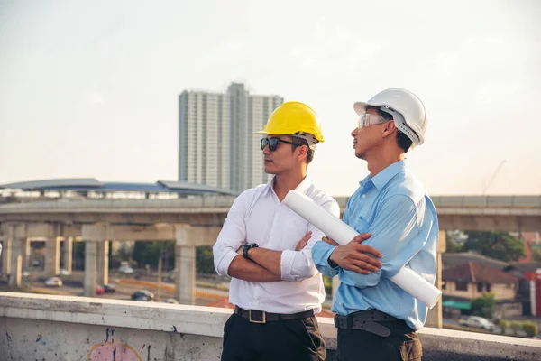 Civil engineer teams meeting working together wear worker helmets hardhat on construction site in modern city. Foreman industry project manager engineer teamwork. Asian industry professional team