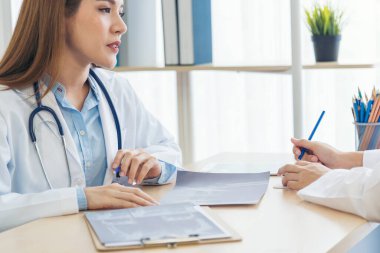 İki Asyalı kadın el doktorları buluşması reçeteli sağlık kliniği yazıyorlar. Doktor dizüstü bilgisayarı kullanarak tartışır. İki kadın doktor laboratuarının ellerini kapayarak sağlık hizmetleri ekip çalışmasını tartışıyorlar.