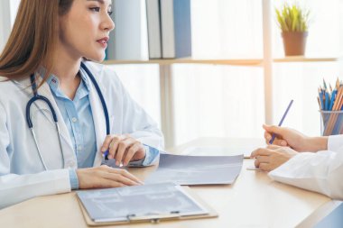 İki Asyalı kadın doktor dizüstü bilgisayarlı hasta danışmanlığı kullanarak doktorun muayenehanesiyle görüşmeyi tartışıyor. Asya tıp laboratuarındaki genç kadınlar birlikte sağlık hizmetleri ekip çalışmasını tartışıyorlar.